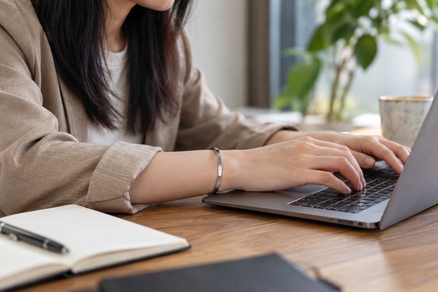 Illustration: Close-up of a Chinese adult hand wearing a simple stainless steel bracelet during normal desk work, natural candid photo